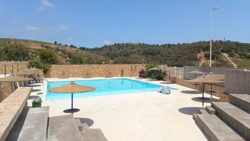 a swimming pool with umbrellas in front of a building at Appartement calme avec piscine et proche de la plage in Fnidek