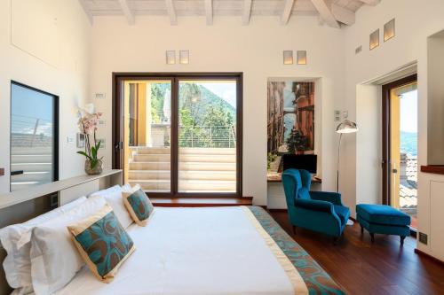 a bedroom with a large white bed and a blue chair at Luxury Como Lake - Luxury Villa with Infinity Pool in Blevio