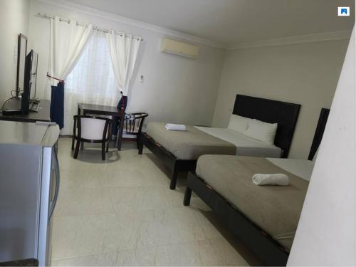 a room with three beds and a desk and a television at Venezia Suites Resort Panglao in Panglao Island