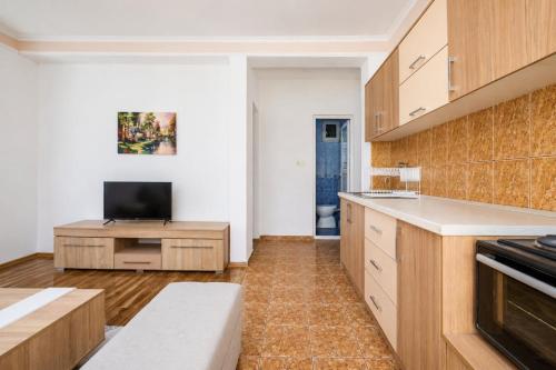 a kitchen with wooden cabinets and a flat screen tv at Markovi A&V in Gevgelija