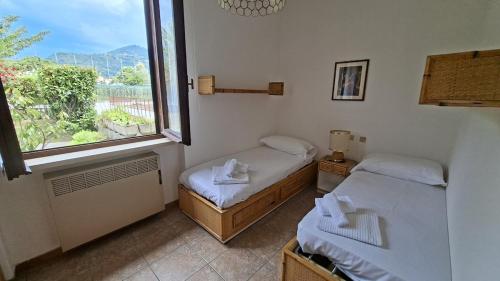 two beds in a room with a window at Lesa Lake House in Lesa