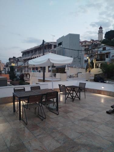 a patio with tables and chairs and an umbrella at Zante Art de l'eau in Zakynthos