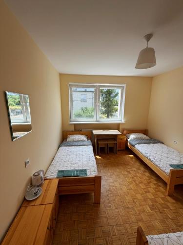 a room with two beds and a table and two windows at Górna Residence&Rooms in Grudziądz