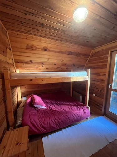 a bed in a cabin with a wooden ceiling at Vikendica Lovinovic Vlasic in Šišava