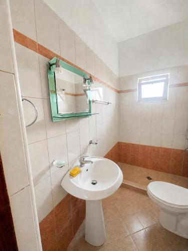 a bathroom with a sink and a toilet and a mirror at Tale Breeze Apartments in Tale