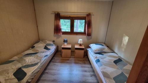 two beds in a small room with a window at Amber coast - domek nr 5 in Jantar