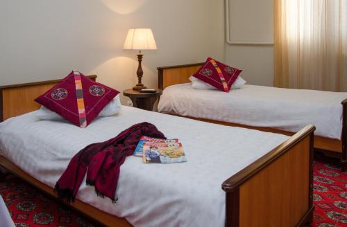two beds in a hotel room with a robe on them at Jipek Joli Inn in Nukus