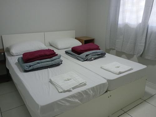 a white bed with two pillows on top of it at Recanto da Colônia in Ponta Grossa
