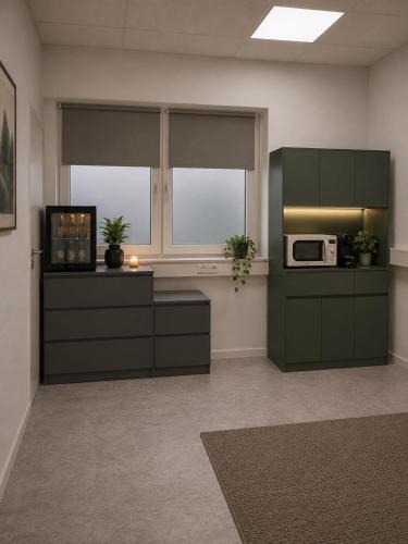 a kitchen with green cabinets and a microwave at MeBa Living Business Suite Mönchengladbach in Mönchengladbach
