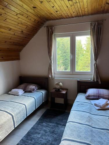 two beds in a room with a window at House Bozovic in Žabljak