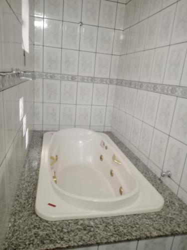 a white bath tub in a white tiled bathroom at Pousada Exclusiva in Rondonópolis