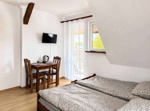 a bedroom with a bed and a table and a window at Pensjonat Rowy Blisko Morza in Rowy