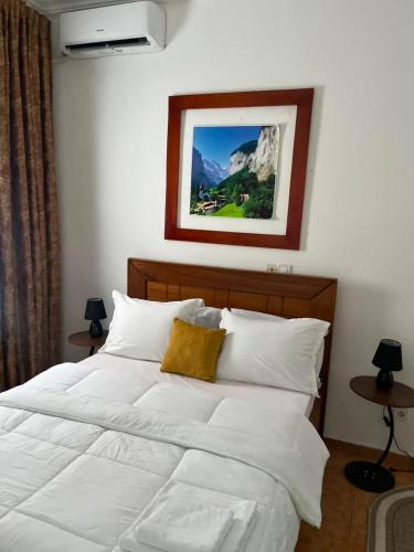 a bedroom with a white bed with a picture on the wall at SWISS Residence Denver in Douala