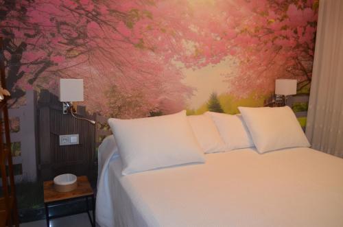a bedroom with a white bed with a painting at Casa del Sol y la Luna Apartamento Amanecer in Tíjola
