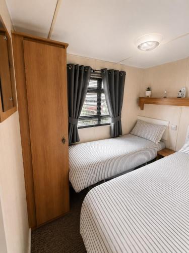 a small room with two beds and a window at The Hemsbee Static caravan 117 Sandsgate Hemsby in Hemsby