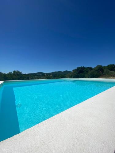 a swimming pool with blue water and trees in the background at Chambre cosy in Viols en Laval