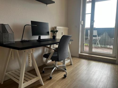 a desk with a computer and a chair in a room at Ruhiger Flussblick vom Balkon all-in 5G in Gera