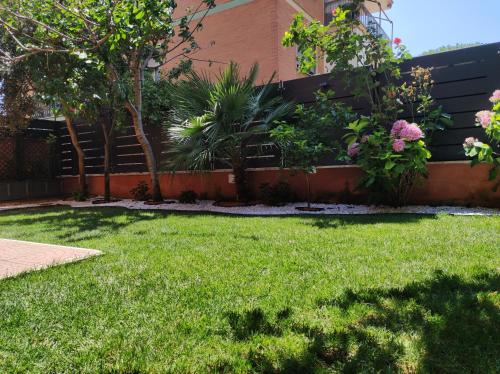a yard with green grass and trees and a building at Eden Bay Vacation Home in Ladispoli