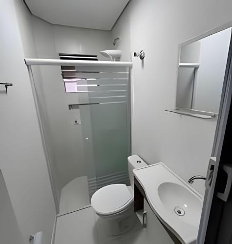 a white bathroom with a toilet and a sink at Estadia Perfeita com AC, Apto a minutos do Aeroporto Gru in Guarulhos