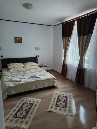 a bedroom with a bed and two rugs on the floor at Pensiunea Narcisa cu Ciubar in Mălăeşti