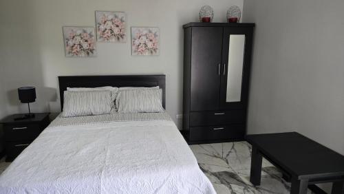 a bedroom with a bed with a black dresser and a mirror at Apartamento Decrusi in Alajuela