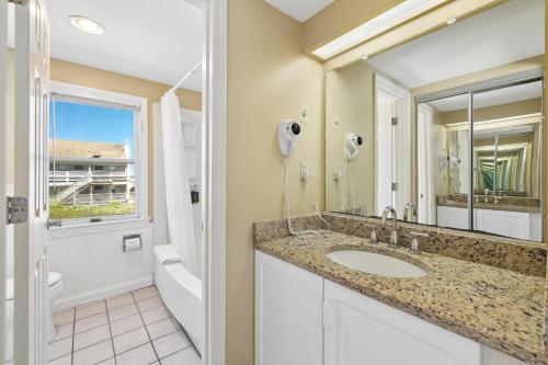 a bathroom with a sink and a mirror at The Corsair & Cross Rip Oceanfront in Dennis Port