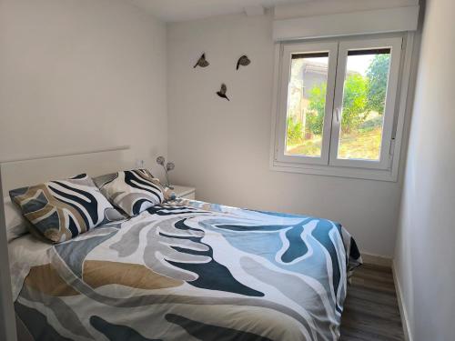 a bedroom with a bed with a comforter and a window at VuT El Mirlo in Frías