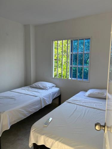 two beds in a room with a window at Cartagena Visible Casa de Huéspedes in Cartagena de Indias