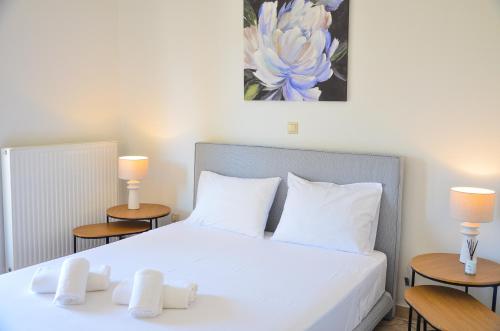 a bedroom with a white bed with two tables at Angie's Serenity Apartment in Vathí