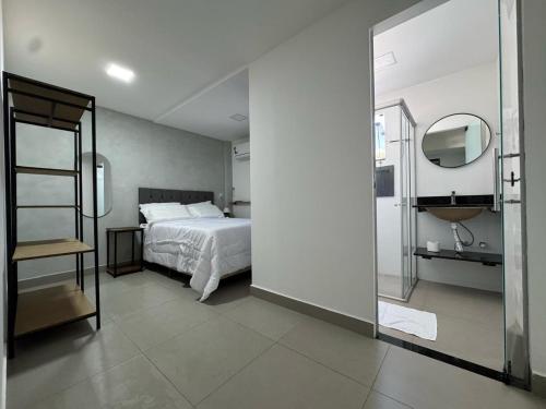 a bedroom with a bed and a bathroom with a mirror at M e M executivo in Ipatinga