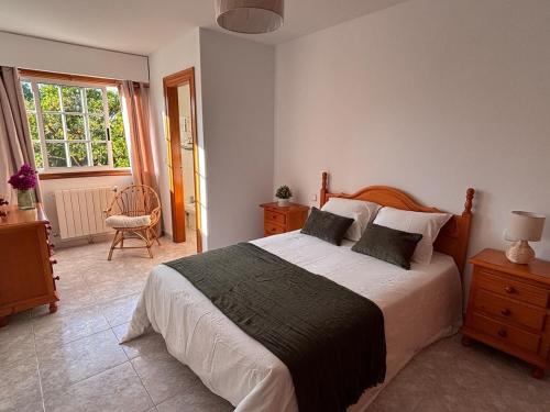 a bedroom with a large bed and a window at Cumbre- chalet con piscina cubierta y vistas al mar en Sada in Sada