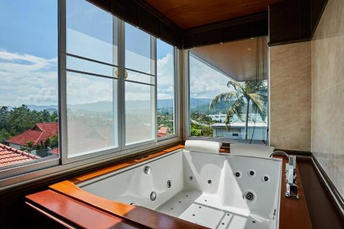 a bath tub in a room with a large window at NB Villa Vimana in Bang Rak Beach