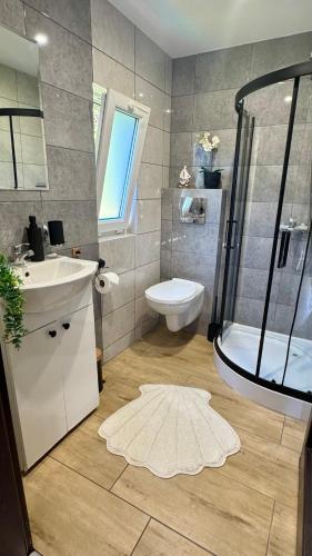 a bathroom with a shower and a sink and a toilet at Domki na Wesołej 2 in Połczyno