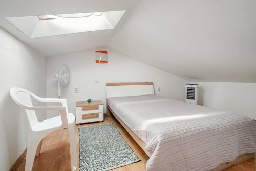 a white bedroom with a bed and a chair at Maremy in Zadar