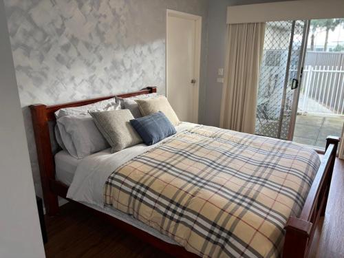 a bedroom with a bed with a plaid blanket at Guest ensuite room with private entrance in Melbourne