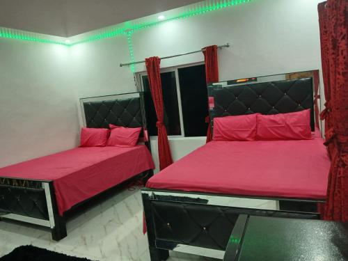 a bedroom with two beds with red sheets and a window at Skyview Palace in Morant Bay