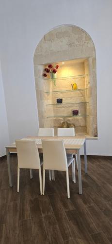 a dining room table with white chairs and a wall at G & N Luxury House in Lecce