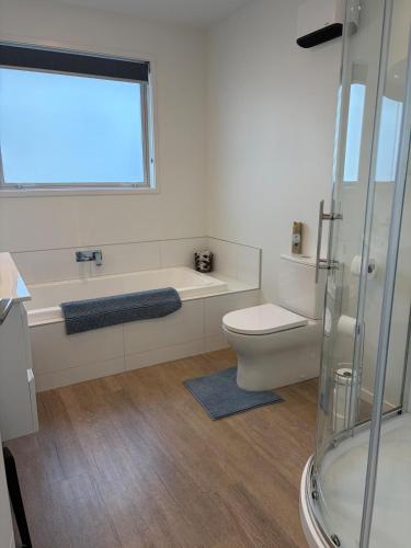 a bathroom with a tub and a toilet and a window at Carters Beach Escape in Carters Beach
