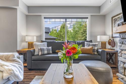 a living room with a couch and a table with flowers at Rocky Mountain Condo with views of Grotto Mtn and hot tub in Dead Man's Flats