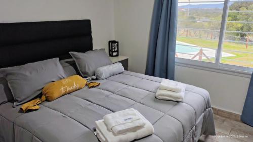 a bed with towels on it in a room with a window at Cabañas Altos del Sauce in Villa General Belgrano