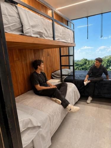 two men sitting on bunk beds in a room at Destinar Tiny House in San Pedro