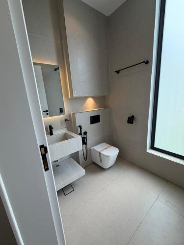 a white bathroom with a sink and a toilet at Al Badr Villas Resort in Sawdāʼ