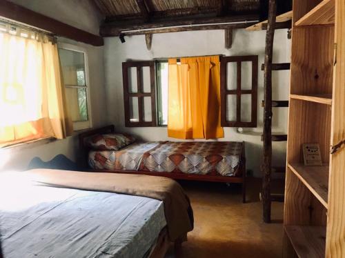 a bedroom with two beds in a room with windows at Espacio Circular Eco Hostel in San Marcos Sierras