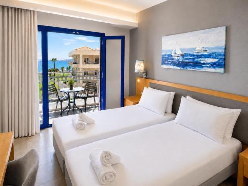 two beds in a hotel room with a balcony at Sergiani Garden Hotel Apartments in Stalís