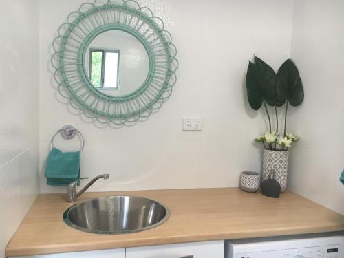 a bathroom with a sink and a mirror at Brodie Beach Bungalow in Coffs Harbour