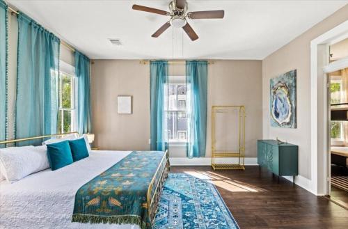 a bedroom with a bed with blue curtains and a ceiling fan at Sand and Sea Manor in Galveston