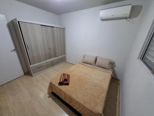 a small bedroom with a bed and a closet at Apartamento com sacada, estacionamento e piscina in São Leopoldo