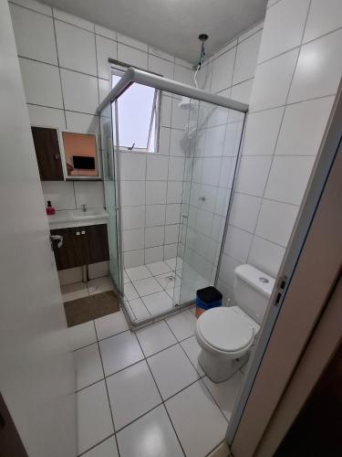 a white bathroom with a toilet and a shower at Apartamento com sacada, estacionamento e piscina in São Leopoldo