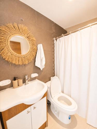a bathroom with a toilet and a sink and a mirror at Resort Playa Azul Departamentos Frente al Mar in Tonsupa