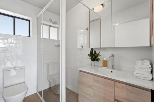 a white bathroom with a toilet and a sink at Hudsons Hideaway - Cosy Eco Cabin, Rainforest Walks in Dorrigo